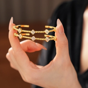 Vista dettagliata di bracciali a perline placcati oro 18k con motivi a quadrifoglio in zirconi
