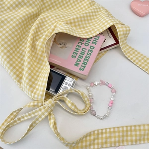 Detail view of yellow plaid canvas tote bag with drawstring and daily essentials inside