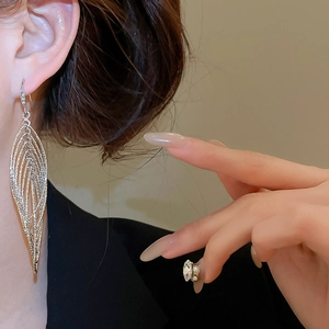 Gros plan de grandes boucles d'oreilles feuilles évidées en argent portées par un modèle