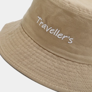 Detailed close-up of the white Traveller's embroidery on a khaki cotton bucket hat