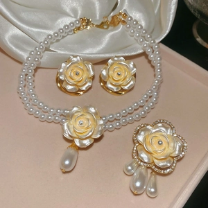 Détail de l'ensemble collier, boucles d'oreilles et broche en perles sur fond de soie