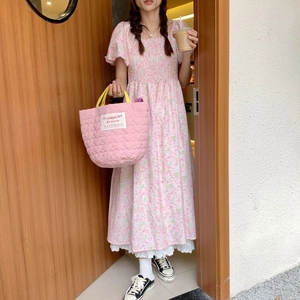 Détail du sac à main matelassé rose en forme de cœur avec anse jaune et robe à fleurs
