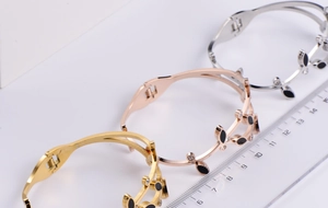 Detail view of leaf-shaped spring bracelets with black enamel and rhinestones in three colors