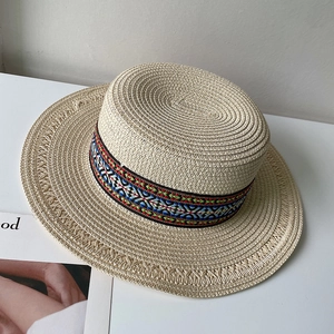 Detail of bohemian woven straw hat featuring colorful ethnic geometric patterned ribbon