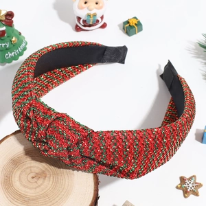 Detail of festive knotted headband with red and green glitter stripes on wood base