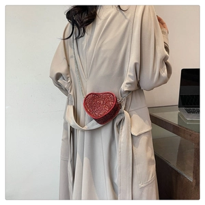 Fashionable red heart rhinestone mini bag with silver chain strap worn by a model