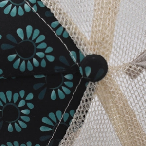 Detailed close-up of teal floral print and breathable beige mesh on a ponytail baseball cap