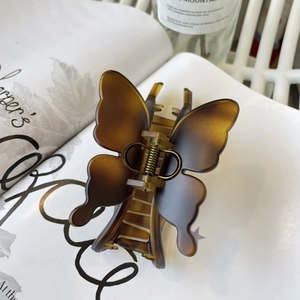 Detail of a large butterfly hair claw in brown gradient resin on a minimal background