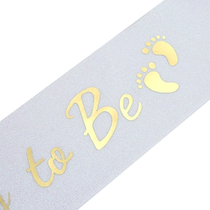 Macro detail of lavender glitter sash with gold Mom to Be lettering and baby footprints
