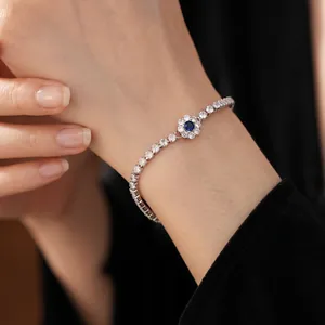 Sparkling silver tennis bracelet featuring a blue stone flower centerpiece on a model wrist