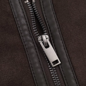 Close-up detail of dark brown suede jacket featuring a gun-gray metal zipper and leather trim