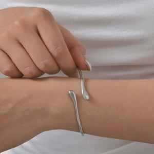 Minimalist silver stainless steel open bangle featuring a polished teardrop design for women