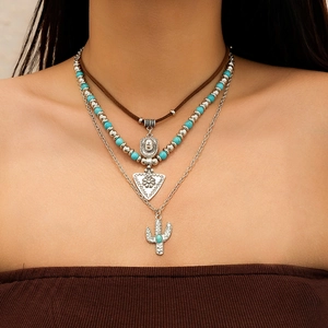 Detail of layered bohemian necklace with turquoise beads and silver cactus pendant