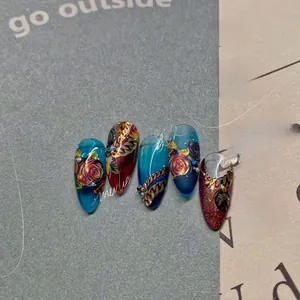 Détail macro de faux ongles stiletto gothiques avec roses rouges et chaînes en métal
