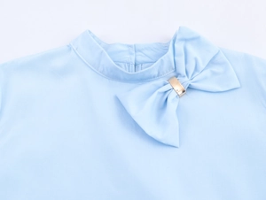 Detail of light blue blouse collar with elegant bow and golden square metal buckle