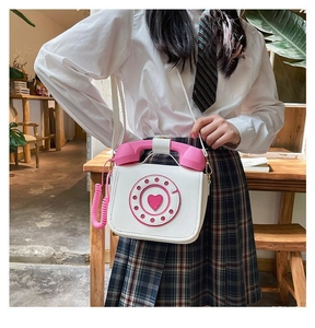 Detail of creative vintage telephone-shaped crossbody bag with pink receiver handle
