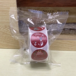Detail of red Christmas stickers on roll with snowman and bell patterns in clear packaging