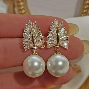Close-up of baroque style pearl earring with sparkling zircon wheat ear pattern in gold