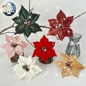 Detail of teal velvet poinsettia flowers with hollow butterfly and red berry accents