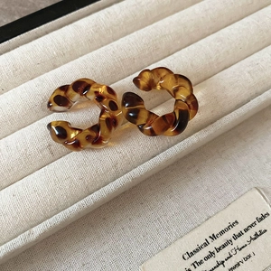 Close-up of leopard print resin C-shape hoop earrings with twisted texture on velvet tray