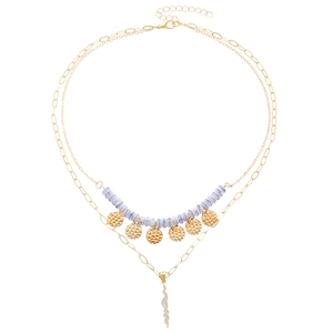 Dettaglio di collana boho a strati con perle marmorizzate e ciondolo a saetta oro