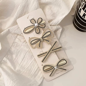 Detail of 4-piece hair clip set with white pearls, gold alloy, and black woven accents