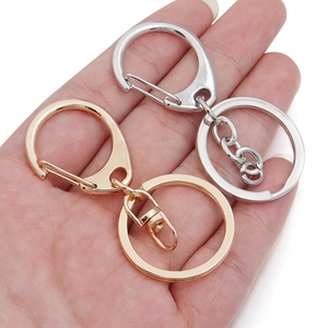 Golden and silver D-shaped lobster clasp keyrings held in hand for size visualization
