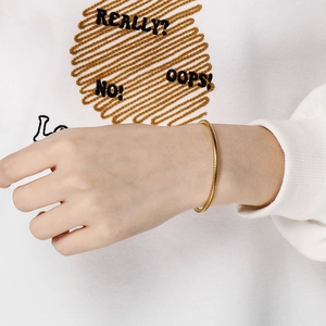 Minimalist gold snake chain bracelet with press clasp on wrist in a stylish shot