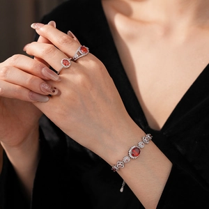 Close-up of sparkling ruby zircon flower bracelet and oval ring on velvet sleeve