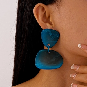 Détail de boucles d'oreilles pendantes géométriques en acrylique bleu sur un mannequin