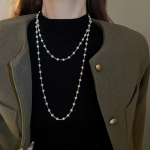 Détail d'un long collier de perles à double rang avec chaîne dorée sur un mannequin