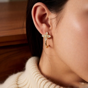 Detail view of vintage C-shaped gold flower earrings with pavé zircon stones on ear