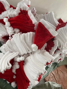 Detailed close-up of bulk red and white velvet Christmas hats in a storage warehouse