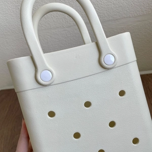 Close-up of cream EVA tote bag showing hole patterns and handle rivet details