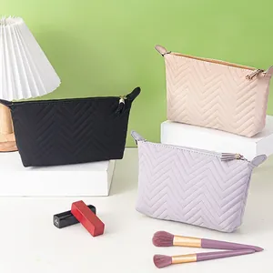 Quilted dumpling makeup bags in black, pink, and grey with tassel and gold zippers