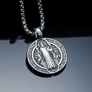 Macro detail of silver Saint Benedict medal pendant with intricate Latin engraving