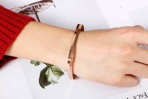 Detailed view of a modern rose gold square-shaped stainless steel bangle worn on a wrist