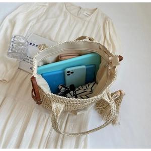 Detailed top view of large straw tote bag featuring woven texture and tassel decor