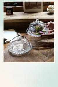 Detail of glass cloche with beaded tray on a vintage wooden table for desserts