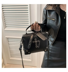 Detail of black punk mini bag with silver cross, metal chain and rivets worn on shoulder
