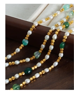 Detailed macro shot of vintage pearl and green stone necklace with golden metal beads