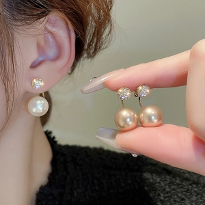 Close-up of double-sided gold plated stud earrings with zircons and large champagne pearls