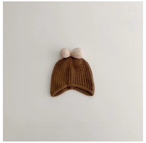 Detail of kids winter knit hat with twin pink faux fur pom-poms and ribbed texture