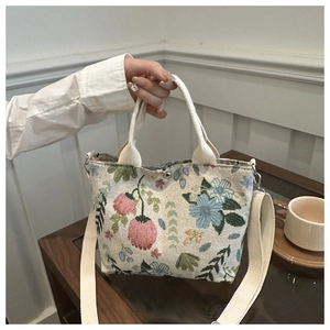 Detailed view of floral embroidery on a canvas tote bag with adjustable shoulder strap