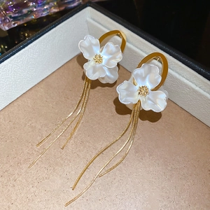 Close-up of elegant flower tassel earrings with white pearlescent petals and gold finish