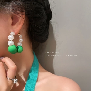 Silver needle pearl hoop earrings with green frosted beads shown on a professional model