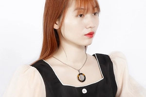 Dettaglio di una collana con ciondolo rotondo e silhouette indossata da una modella