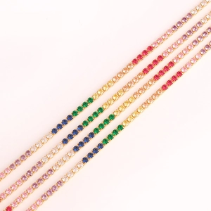 Close-up of four gold tennis bracelets featuring a rainbow gradient of zircon stones
