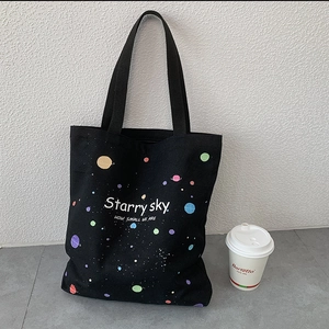 Détail du sac cabas en toile noire avec imprimé coloré de ciel étoilé et de planètes