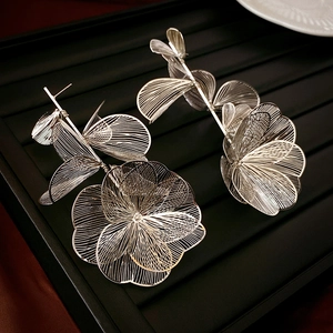 Detailed close-up of large hollow floral tassel earrings in silver brushed metal finish
